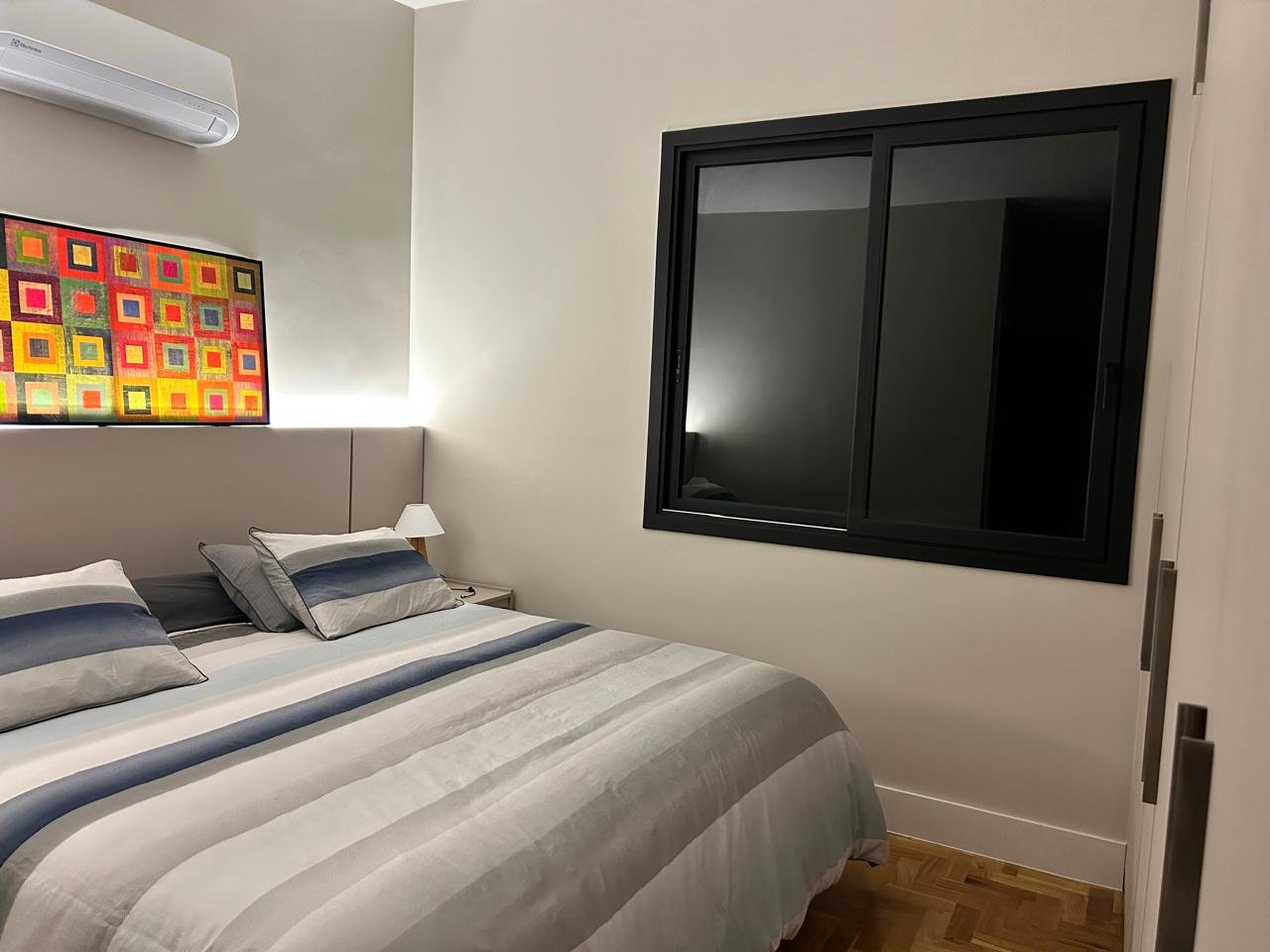 Quarto com paredes claras e esquadrias pretas